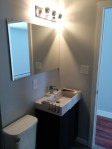 modern bathroom with square sink and stainless steel fixtures and large mirror