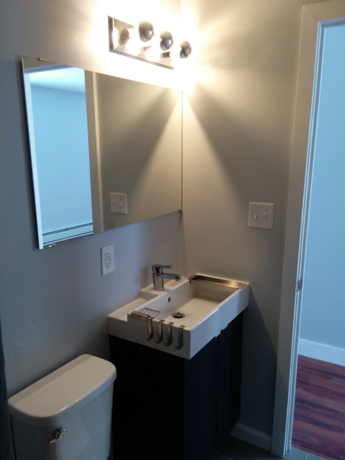 modern bathroom with square sink and stainless steel fixtures and large mirror