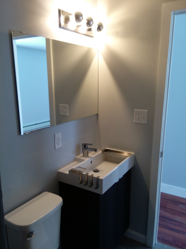 modern bathroom with square sink and stainless steel fixtures and large mirror